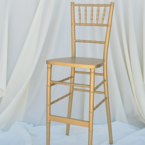 Gold colored Chiavari bar stool in front of  a white backdrop.