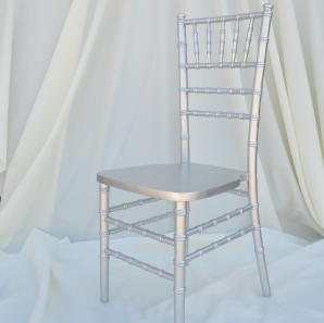 Silver colored Chiavari chair in front of  a white backdrop.