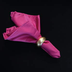 Close up of a hot pink napkin in a gold napkin ring.